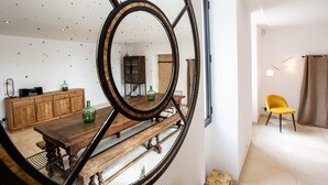 A dining area with a wooden table, benches, and a cabinet. A mirror with a circular frame is mounted on the wall.
