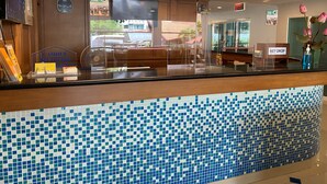 A reception area with a tiled floor, a reception desk, a clock, and a 'Free Zone' sign. - Soi 2 inn Pattaya (Pattaya)