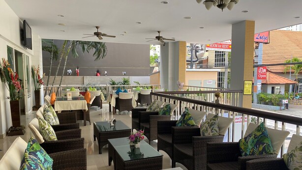 A hotel lobby with wicker furniture, ceiling fans, and a view of the street. - Soi 2 inn Pattaya (Pattaya)