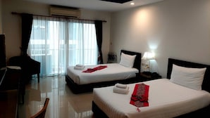 A hotel room with two beds, a desk, a chair, and a view of the outdoors through large windows. - Soi 2 inn Pattaya (Pattaya)