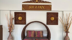 A room with a woven sofa, a glass coffee table, and two large vases with dried plants. - Soi 2 inn Pattaya (Pattaya)