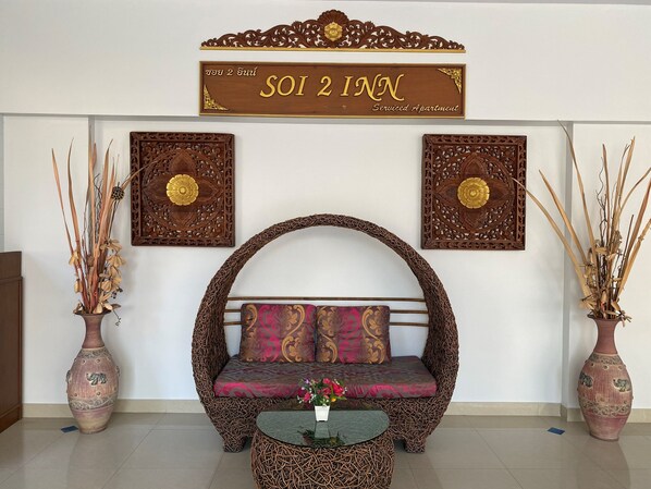 A room with a woven sofa, a glass coffee table, and two large vases with dried plants. - Soi 2 inn Pattaya (Pattaya)