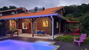 Uma casa com piscina, área de estar externa e uma rede.