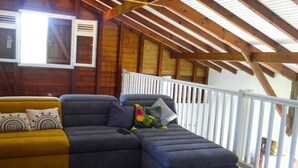 Quarto aconchegante com teto de madeira e corrimão branco.