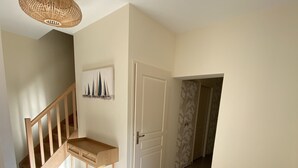 A spacious hallway with a wooden staircase, a bench, a door, and a wall-mounted artwork. - Renovated town house in the heart of Arcachon (Arcachon)