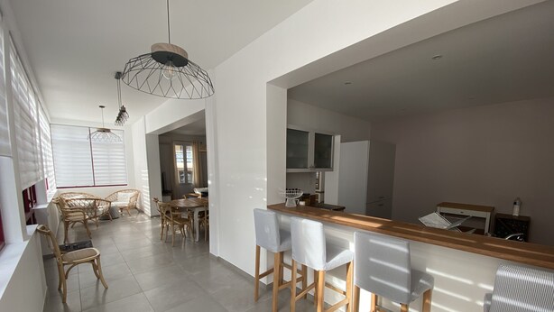 A modern kitchen with white cabinets, a wooden countertop, and bar stools. - Renovated town house in the heart of Arcachon (Arcachon)