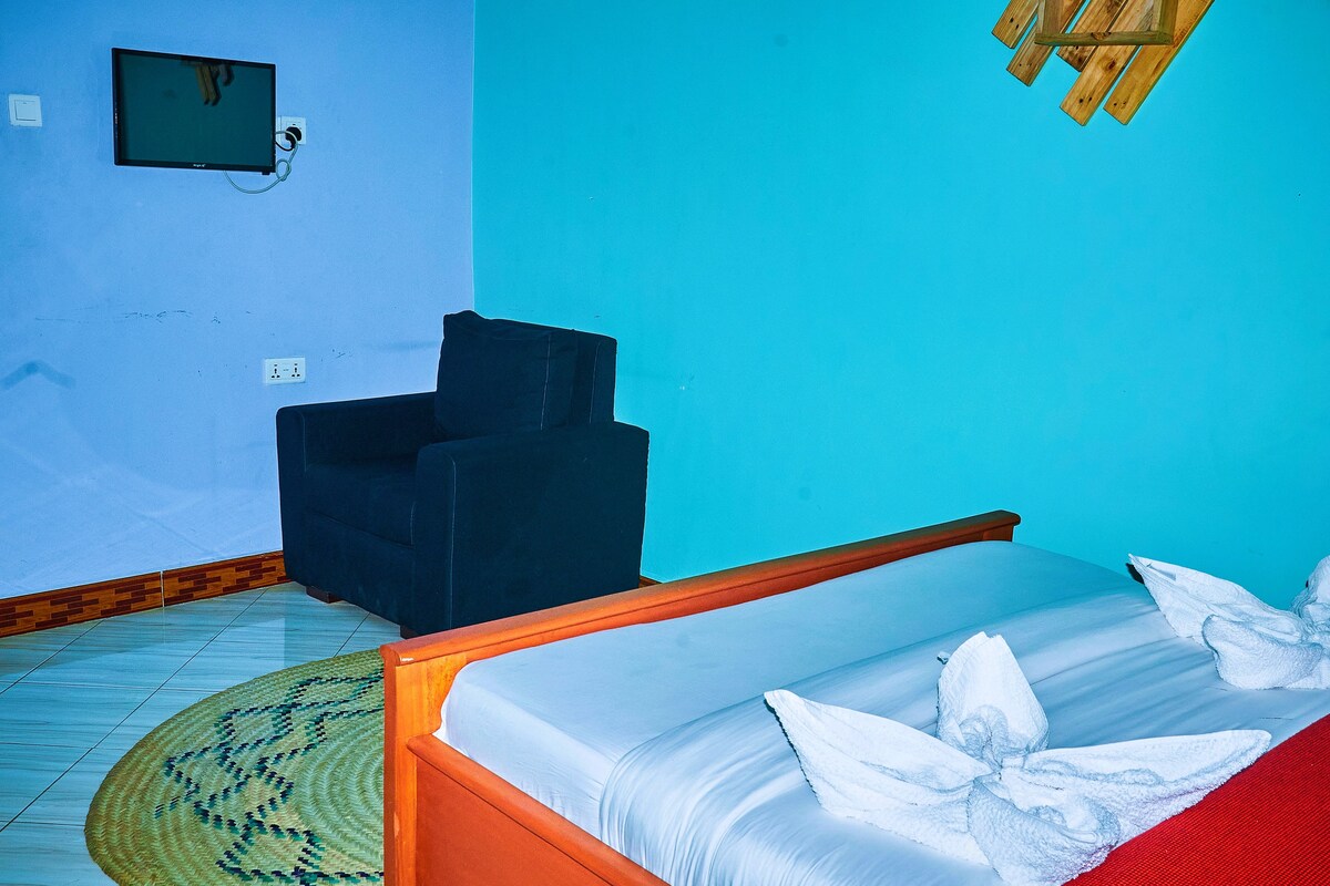 A room with a bed, a chair, and a television mounted on the wall.