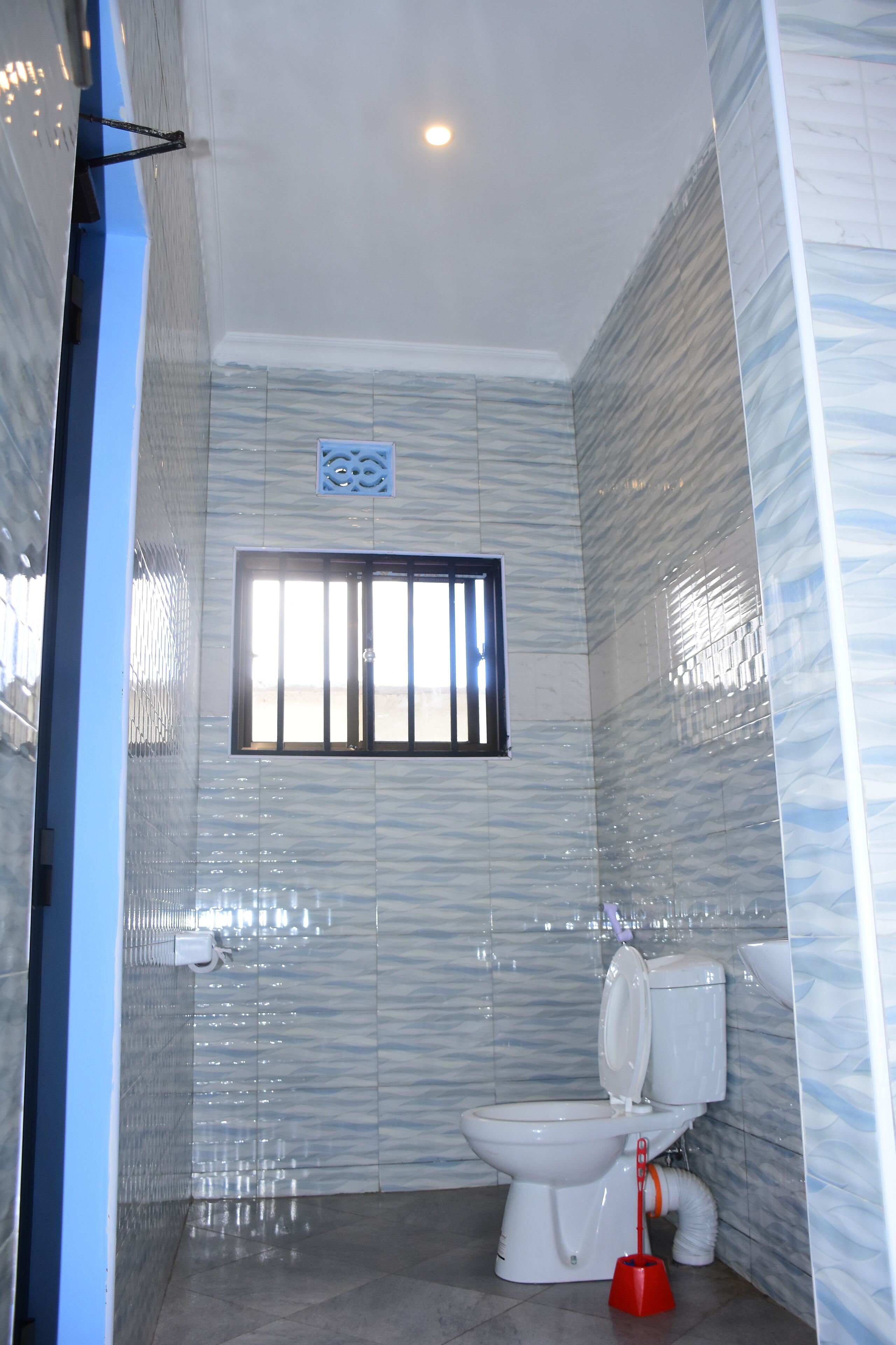 Un bagno con il water, un asciugamani ad aria e una finestra con sbarre.