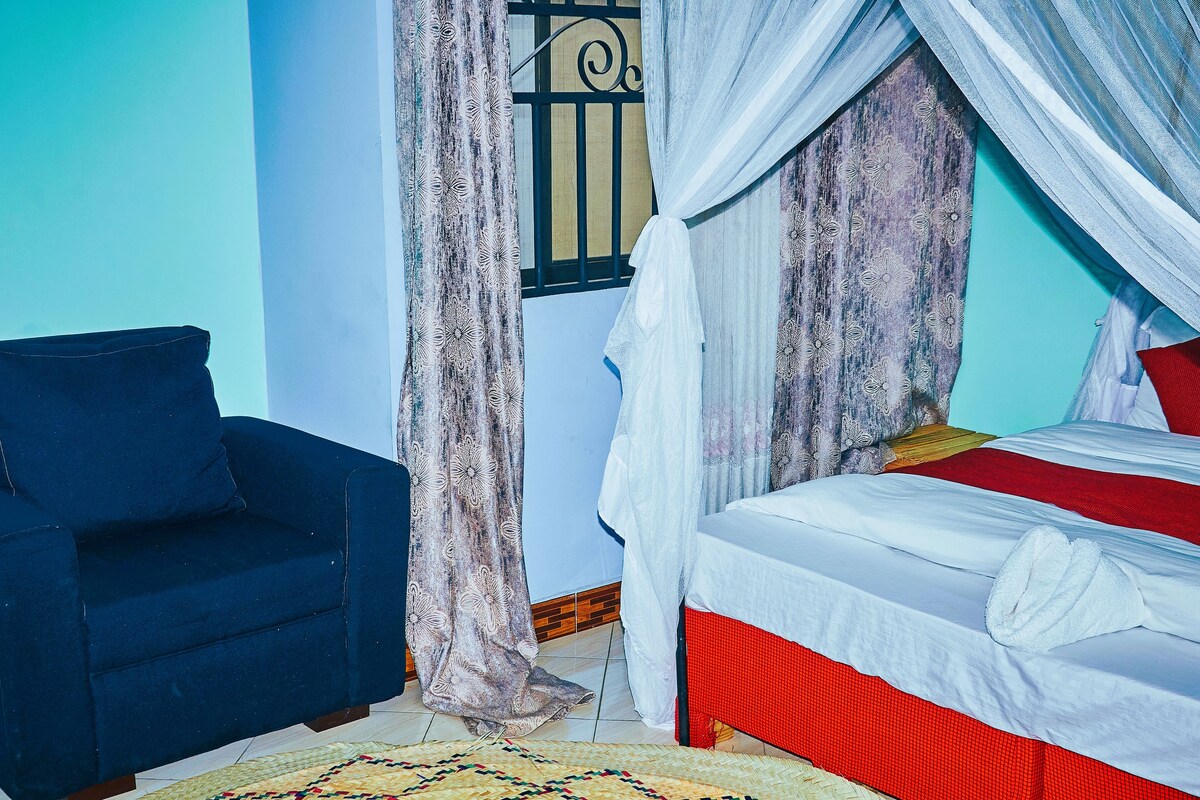 A room with a bed, a blue sofa, and curtains.