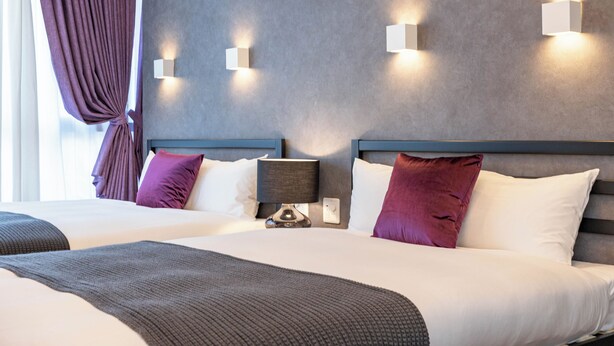 A hotel room with two beds, a nightstand with a lamp, and wall-mounted lights. - ART NAMBA HIGASHI  (Osaka)