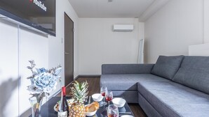 A modern living room with a grey sofa, a dining table with food and drinks, and a YouTube sign on the wall. - ART NAMBA HIGASHI  (Osaka)