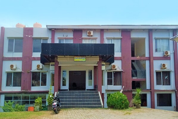 A multi-story building with a sign indicating it is a hotel. There are air conditioning units on the exterior, a staircase leading to the entrance, and a motorcycle parked in front. - OYO 91876 Hotel Putri Gading 2 (Bengkulu)
