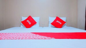 En säng med vita sängkläder och två röda kuddar med ordet ”oyo” på.