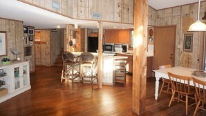 Un interno rustico con pareti in legno, una zona cottura e un'area pranzo con sedie in vimini.
