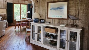 Un interno rustico con un mobiletto in legno, un quadro incorniciato e un'area pranzo con tavolo e sedie.