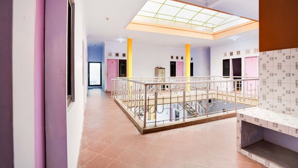 A spacious indoor area with a high ceiling, a glass skylight, and a central open space with a metal railing. - OYO Life 91626 Rr Kost Putri Syariah (Lumajang)