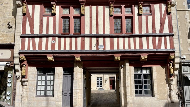 Ein historisches Gebäude mit Fachwerkfassade, Steinmauern und einem Eingang im Erdgeschoss.
