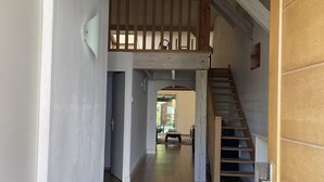 A spacious hallway with a wooden bench, a rug, and a staircase leading to an upper level.