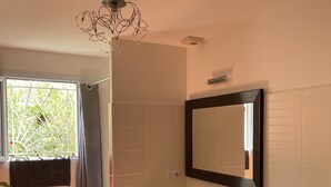 A bathroom with a white sink, a mirror, a shower, and a ceiling fan.