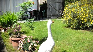A white bird statue in a garden with potted plants and a wooden fence in the background.