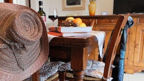 A wooden dining table with a woven basket, a book, and a glass of red wine.