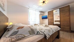 A bedroom with a bed, a TV, a wardrobe, and a window with curtains. - Easy City Access: 3BR w/ Terrace & Private Carport (Zadar)