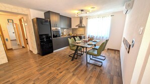 A modern kitchen with a dining area, wooden flooring, and a built-in oven. - Easy City Access: 3BR w/ Terrace & Private Carport (Zadar)