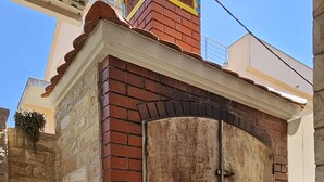A building with a brick facade, a rusted metal door, and a small window with a metal grill. - Easy City Access: 3BR w/ Terrace & Private Carport (Zadar)