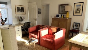 Un salon avec un canapé rouge, une table à manger en bois et un luminaire au plafond.