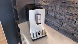 Et moderne køkken med stenvæg, indbygget kaffemaskine og stilfuld bordplade.
