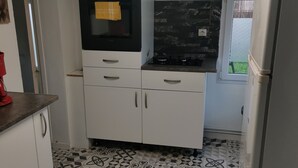 A compact kitchen with a gas stove, white cabinets, and patterned floor tiles. - Charming 70m2 town house 15kms from the sea and 4 kms from Caen. Parking (Giberville)