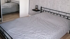 A bedroom with a bed, a nightstand, a mirror, and wall art. - Charming 70m2 town house 15kms from the sea and 4 kms from Caen. Parking (Giberville)