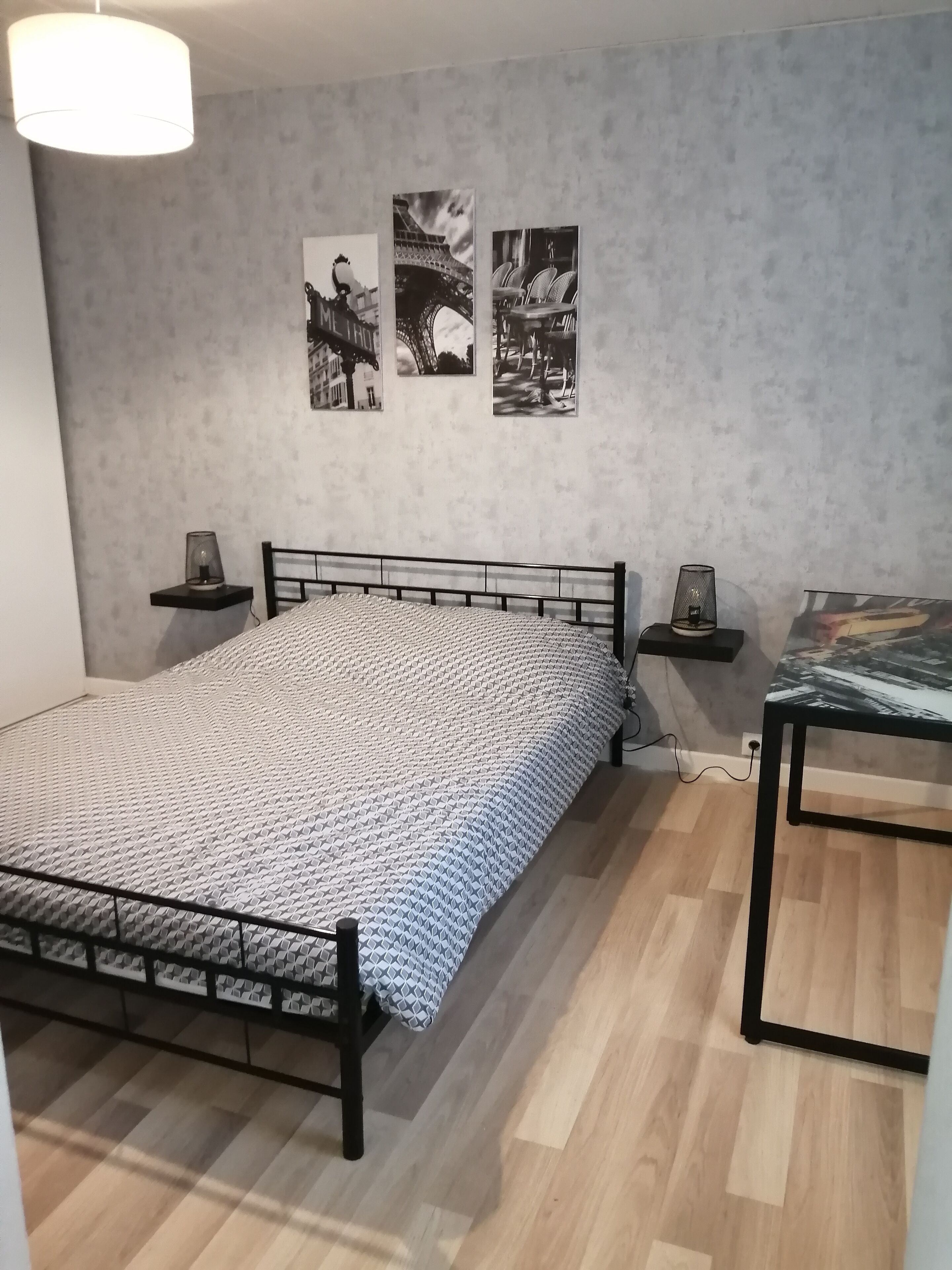 Una camera da letto con un letto, comodini, una lampada e decorazioni a parete.