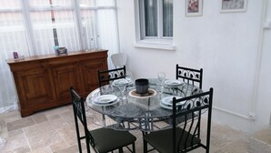 A dining area with a round glass table, black metal chairs, and a wooden cabinet. - Charming 70m2 town house 15kms from the sea and 4 kms from Caen. Parking (Giberville)