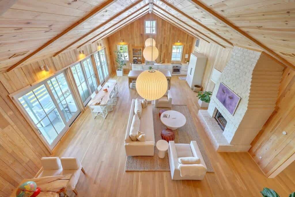 Ein geräumiges Loft mit hohen Decken, Holzwänden, einem Kamin und großen Fenstern.