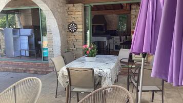 Une terrasse extérieure avec une table et des chaises, un jeu de fléchettes et un parasol violet.
