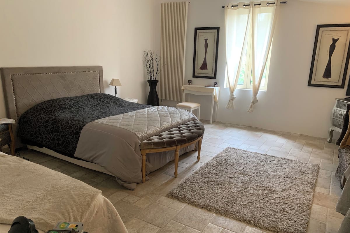 Une chambre à coucher avec un lit, une table de chevet, une lampe et une fenêtre avec des rideaux.
