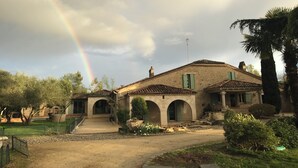 A rustic stone building with a tiled roof, arched doorways, and a small garden with a fountain.