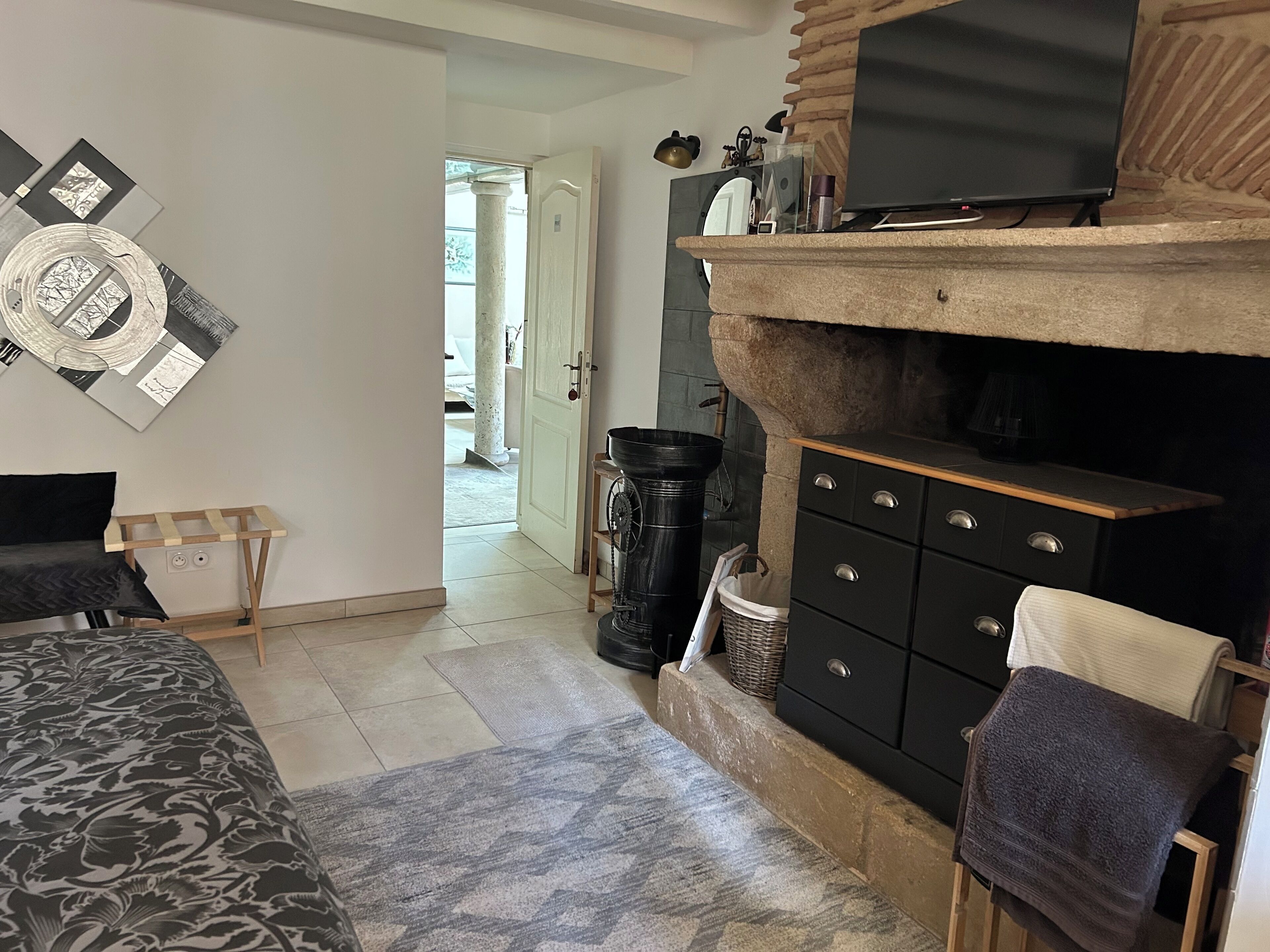 Un dormitorio con cama, tocador, televisor y chimenea.
