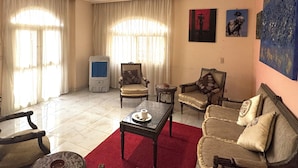 A living room with a red carpet, two armchairs, a sofa, a coffee table, and a ceiling light fixture. - Rino Residential apartment for families (Cairo Governorate)