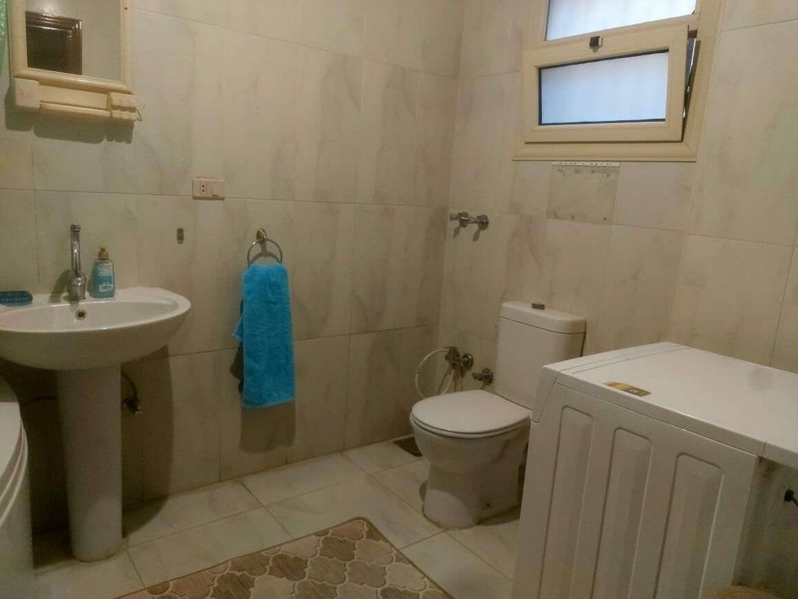 A bathroom with a sink, toilet, and window.