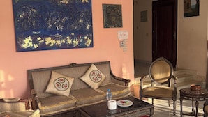 A living room with a sofa, chairs, a coffee table, and a red rug. There is a painting on the wall and a door in the background. - Rino Residential apartment for families (Cairo Governorate)