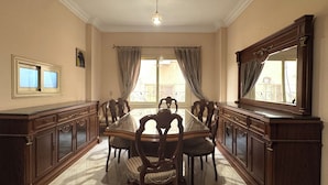 A dining room with a long table, chairs, a chandelier, and a large mirror. - Rino Residential apartment for families (Cairo Governorate)