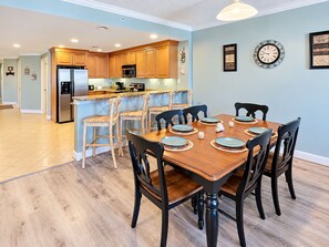 Una cocina moderna con armarios de madera, horno empotrado y comedor con mesa y sillas de madera.