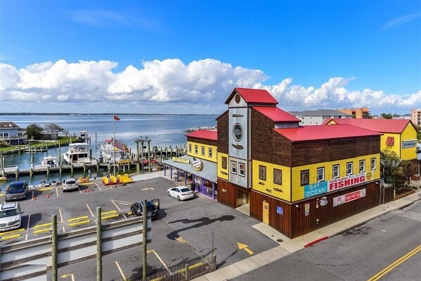 A waterfront building with a clock tower, a bay fishing sign, and a dock with boats. - Luxury 3 Bedroom Bayview Condo with Pool - 22nd St! Overlooking Bahia Marina and Fish Tales! Mariner's Watch #304 (Ocean City)