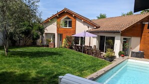 Un immobile residenziale con piscina, patio con mobili da esterno e giardino.