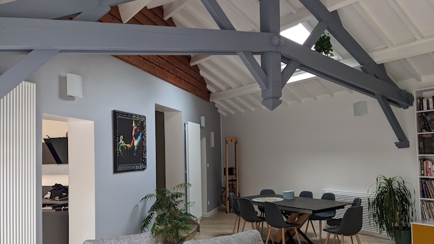 Un'ampia zona giorno con soffitto alto, un tavolo da pranzo con sedie, un divano e una libreria.