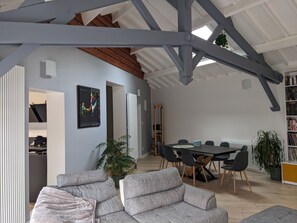 A spacious living area with a high ceiling, a dining table with chairs, a sofa, and a bookshelf. - Large house with swimming pool in Lyon ideal for families, close to transport links (Lyon)