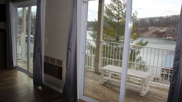 A room with a sliding glass door leading to a balcony with a white bench and railing. - Seaworthy at Wheelhouse Lake Ozark MO (Lake Ozark)