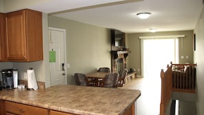 A kitchen with granite countertops, wooden cabinets, and a dining area with a table and chairs. - Seaworthy at Wheelhouse Lake Ozark MO (Lake Ozark)